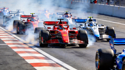 F1大奖赛正赛发车瞬间，多辆赛车在直道上飞驰，轮胎冒起白烟，场面极具速度感