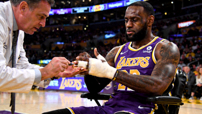 湖人队球星勒布朗·詹姆斯在比赛中手指受伤后接受队医检查