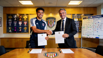 球队经理与核心球员在俱乐部会议室签署续约合同，双方微笑握手