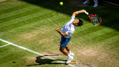 网球运动员张伟在草地球场发球的力量瞬间