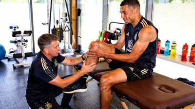 一位球星在队医陪同下进行康复训练，正在检查膝盖伤势