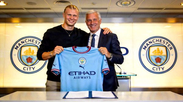 曼城前锋哈兰德在签约仪式上手持新球衣与俱乐部主席合影